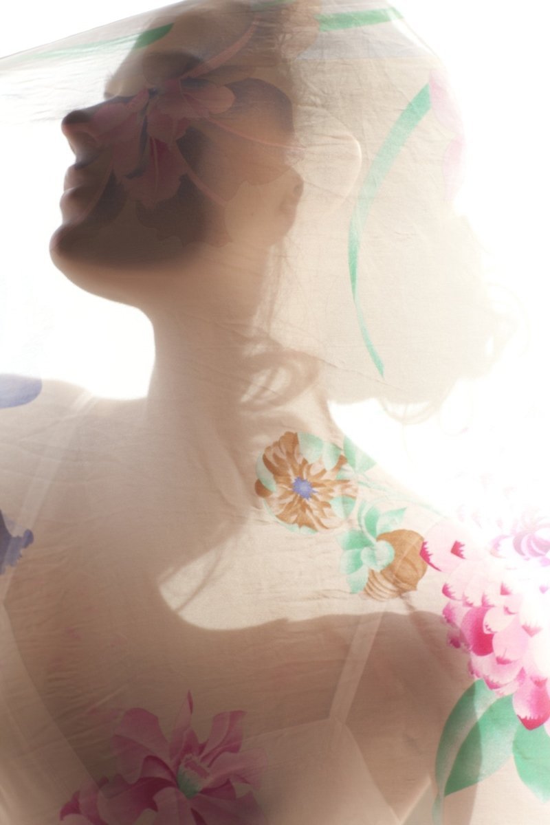 A double exposure photograph showcasing a woman's silhouette overlaid with floral patterns including pink and orange flowers with green leaves.