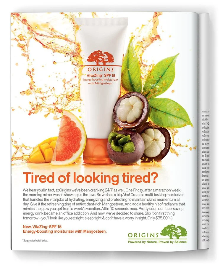 A magazine advertisement for Origins VitaZing SPF 15 moisturizer featuring a tube of the product surrounded by tropical fruits including a grapefruit, mangosteen, and green leaves, with splashes of liquid in the background.