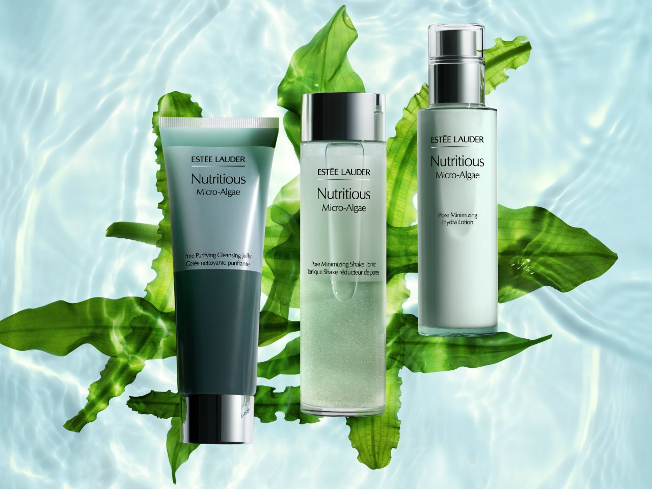 Three Estée Lauder skincare products from the Nutritious Micro-Algae line arranged on green leaves in water. The products include a cleansing jelly, a tonic, and a hydra lotion with clear packaging.