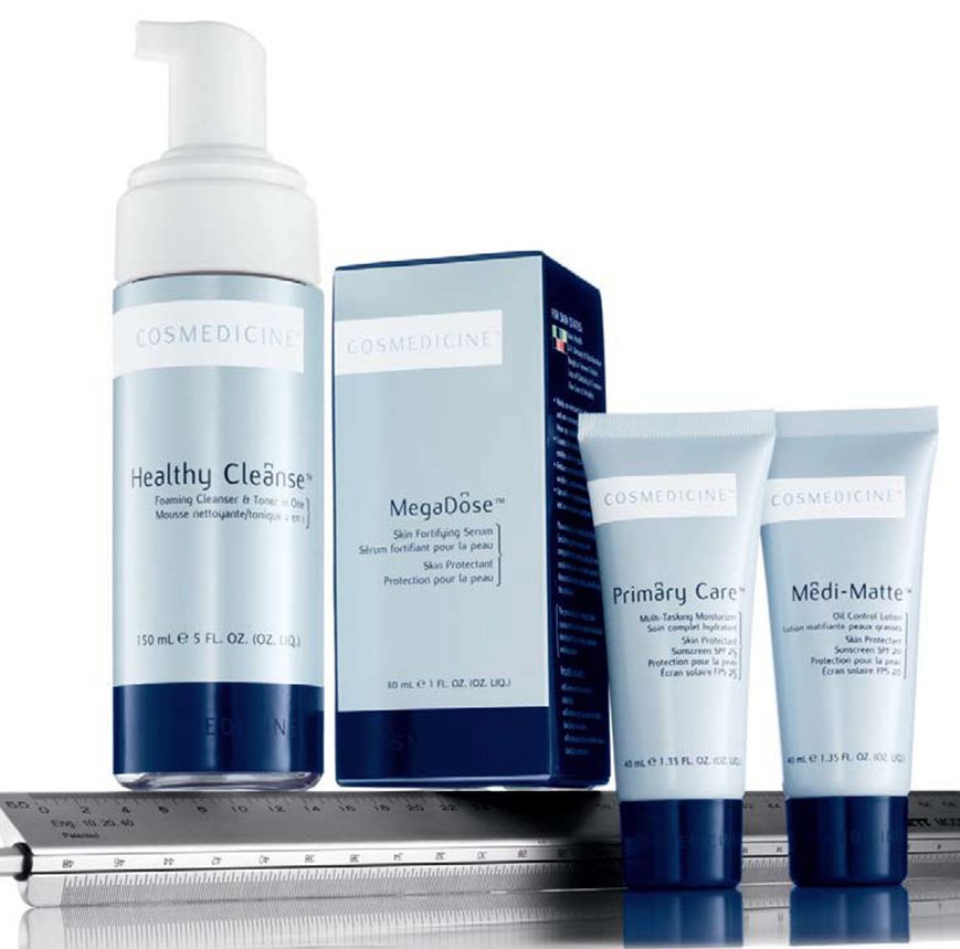 Skincare products including a foaming cleanser, serum, moisturizer, and sunscreen on a surface, with a metal ruler visible in the foreground.