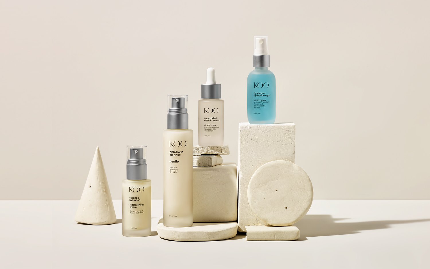 Collection of skincare bottles and containers on geometric white blocks, with a neutral background.