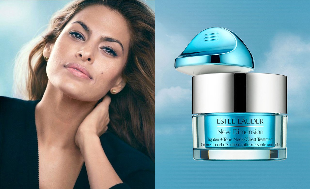 A woman with brown hair and light makeup next to an Estée Lauder New Dimension Tighten + Tone Neck/Chest Treatment jar against a cloudy blue sky background.