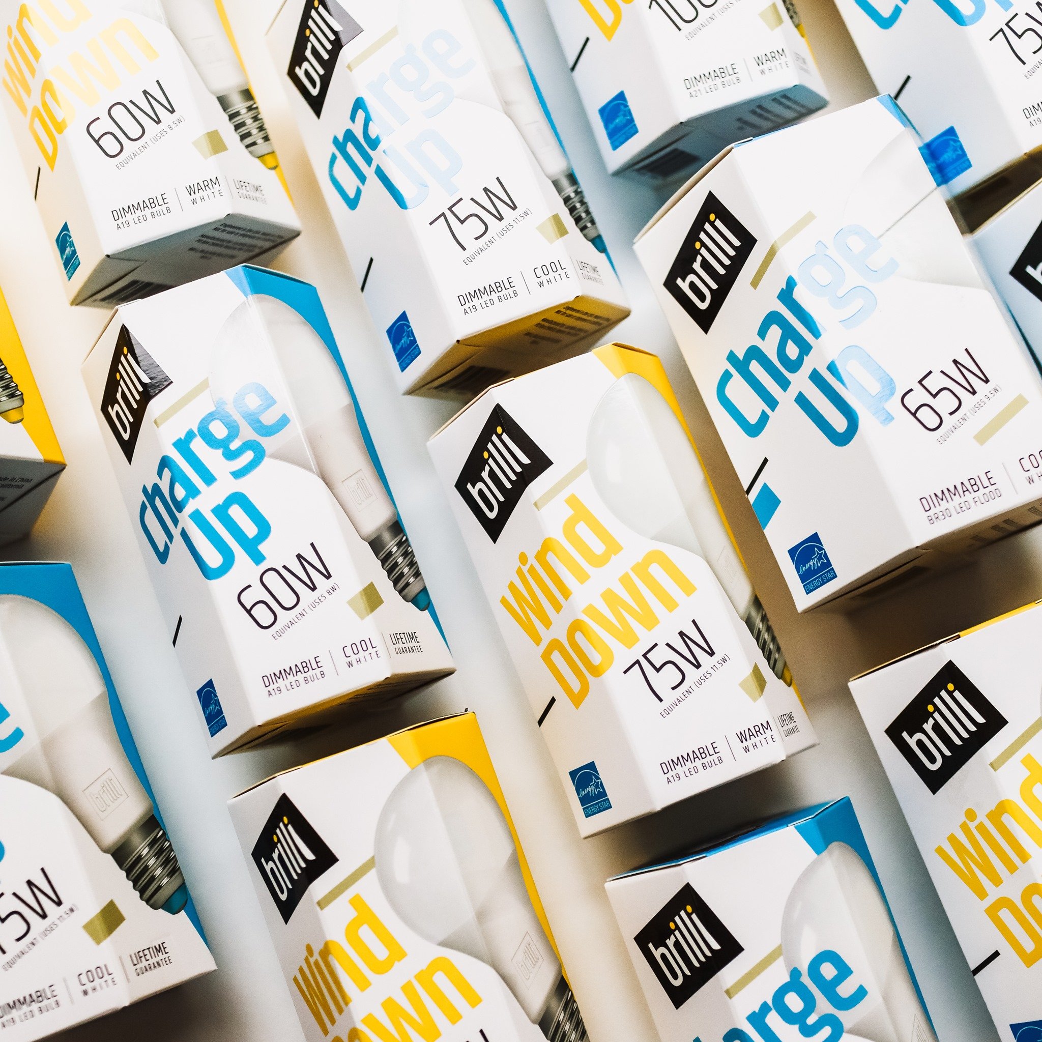 Boxes of Brilli Charge Up and Wind Down LED light bulbs with 60W and 75W labels, arranged closely together.